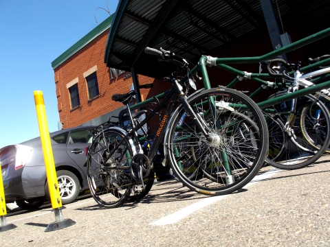 A bicycle is next to a green railing. The bike and the railing are in front of the City Market Downtown Store.