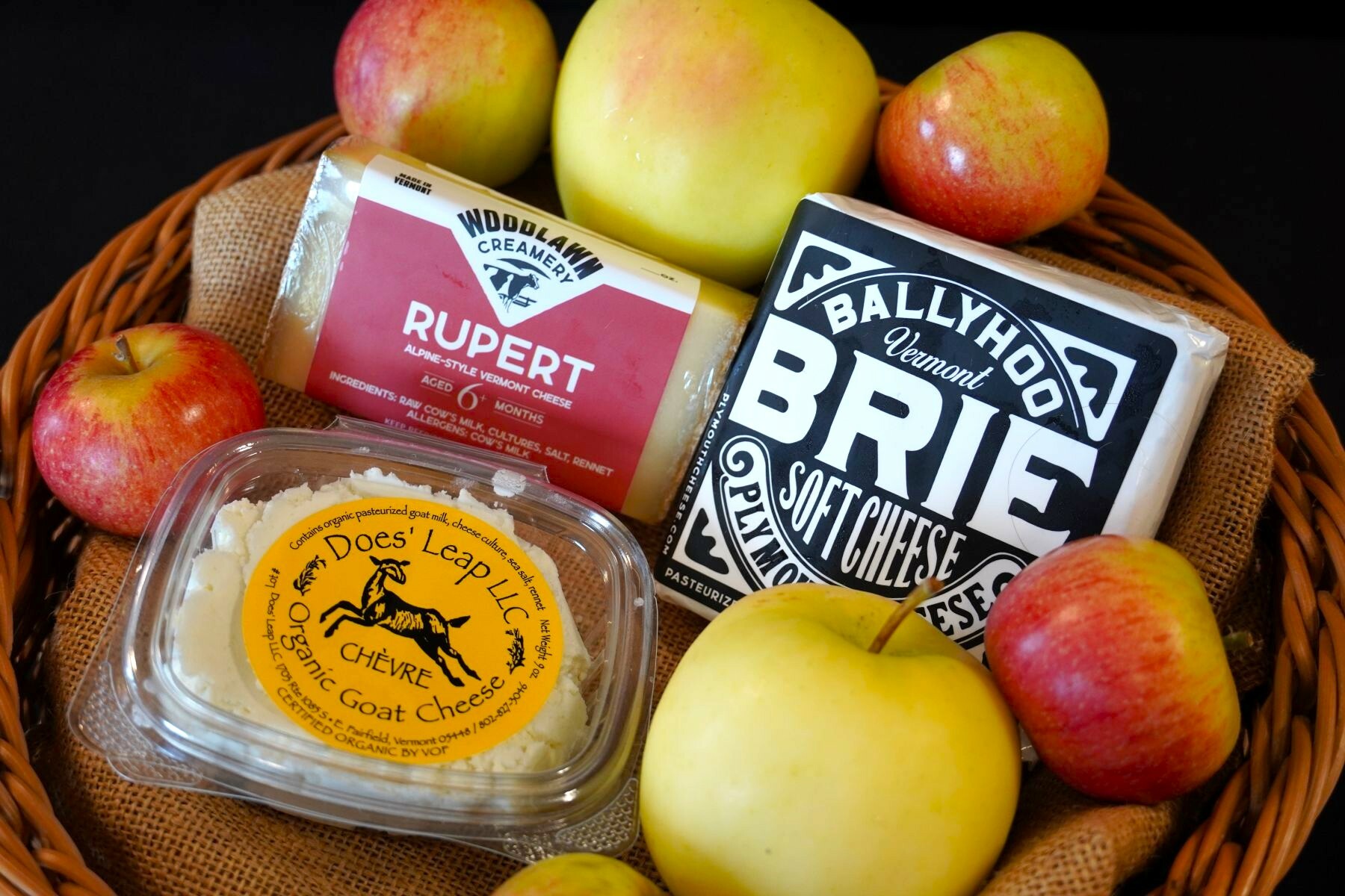 3 kinds of cheeses in a basket with apples