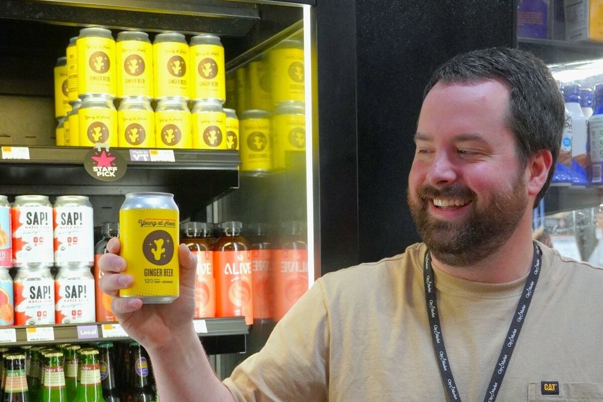 a man holds up a yellow can of ginger beer