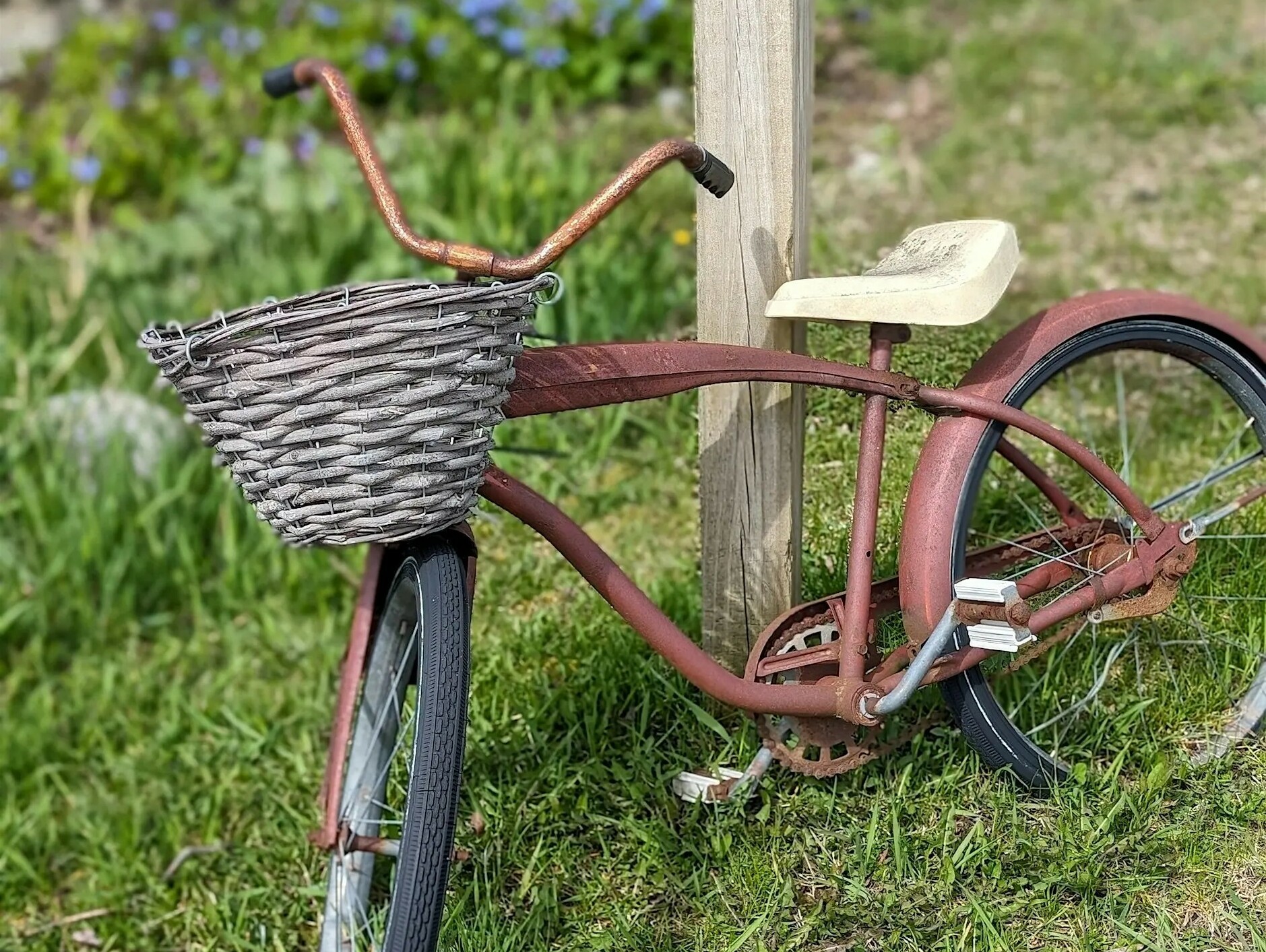 a bike with a wicker basket leaning up against a wooden post