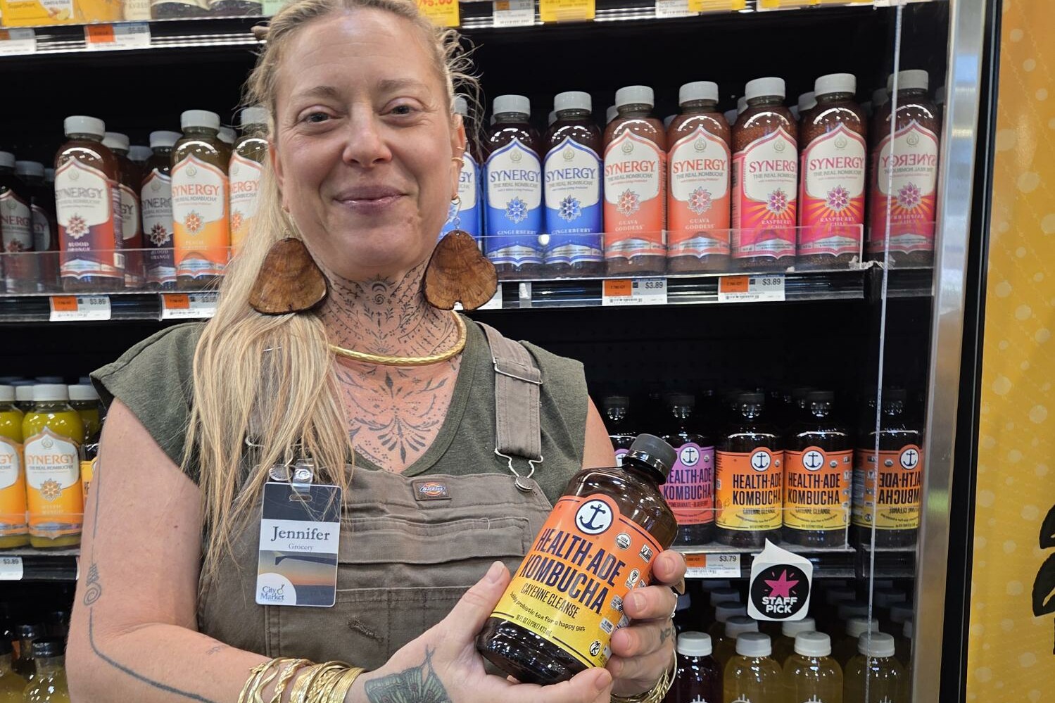 a woman holding up a bottle of kombucha