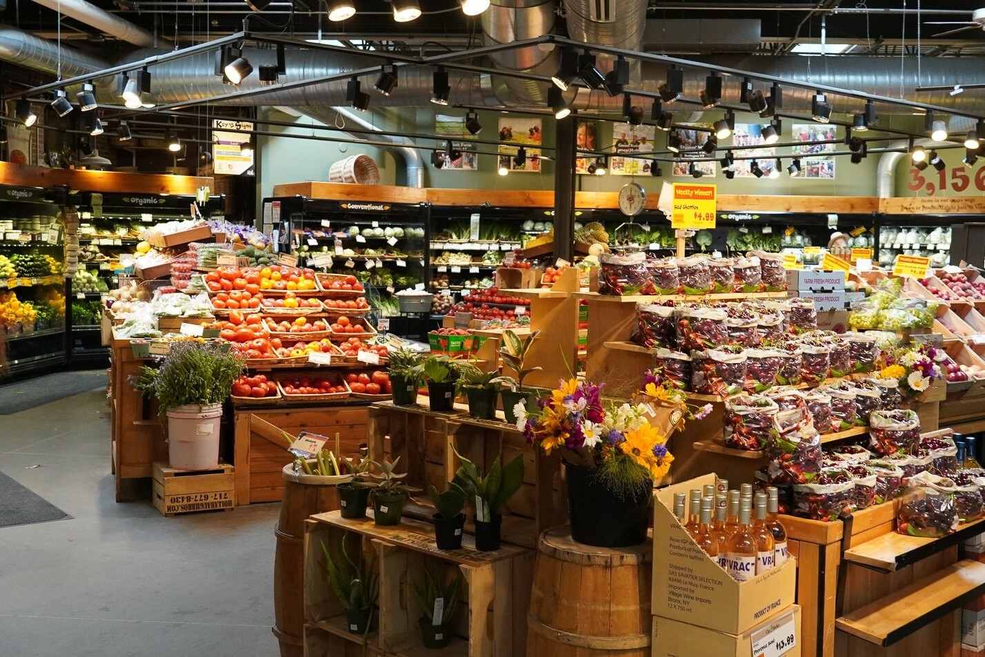 A vibrant grocery store filled with fresh produce, flowers, and decorative displays.