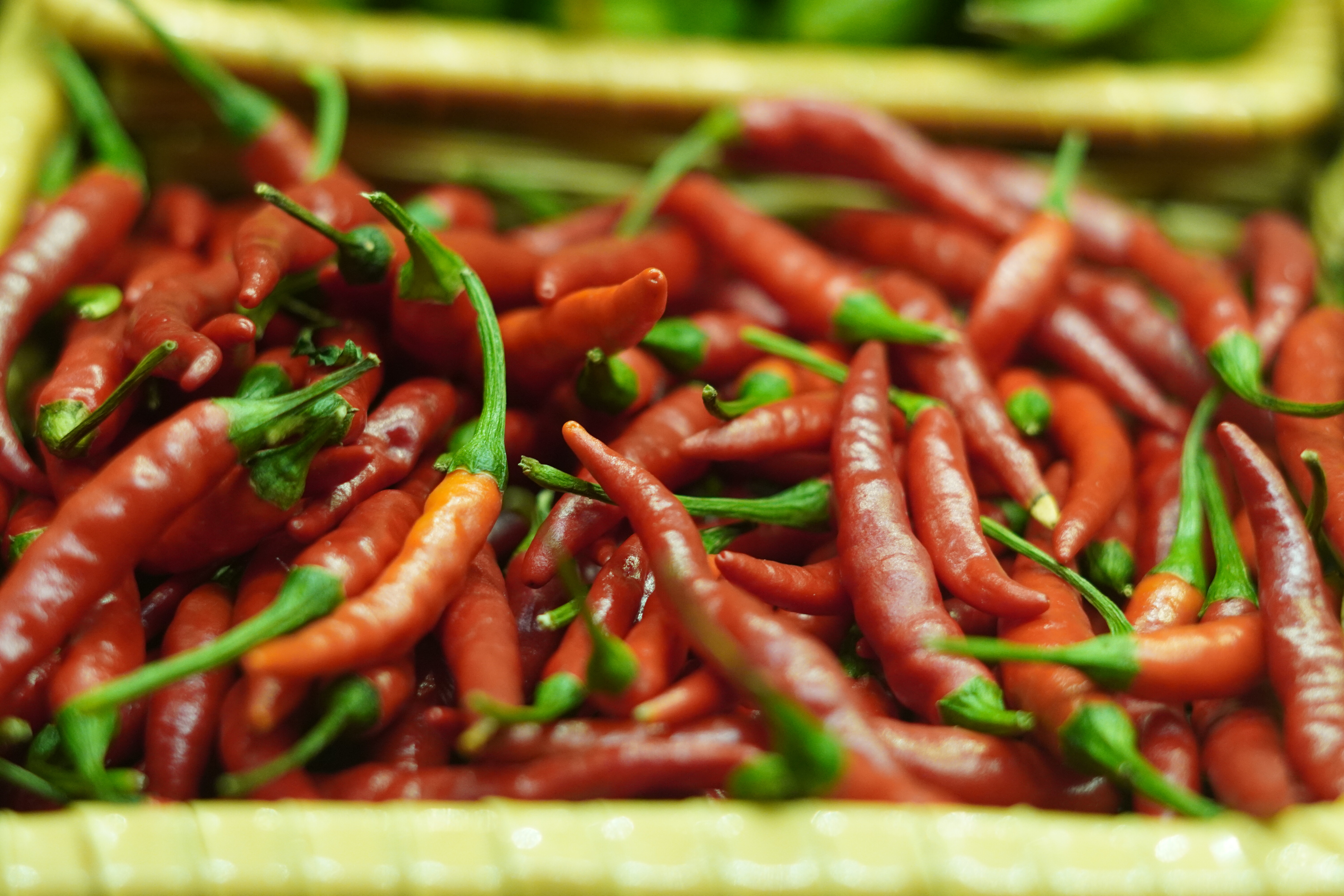 A close-up of vibrant red chilies piled together in a basket.