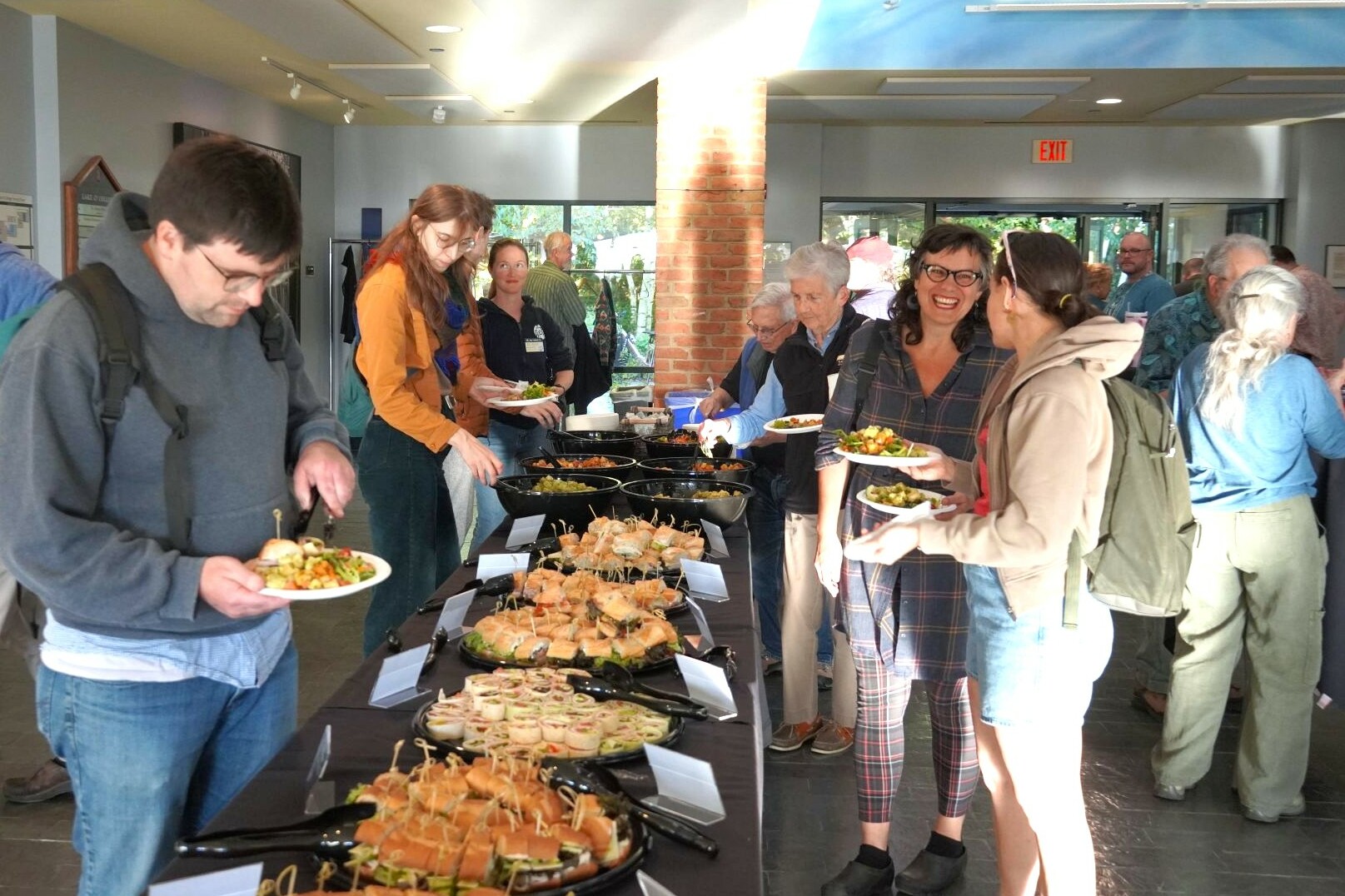 people adding food to their plates from a table of food