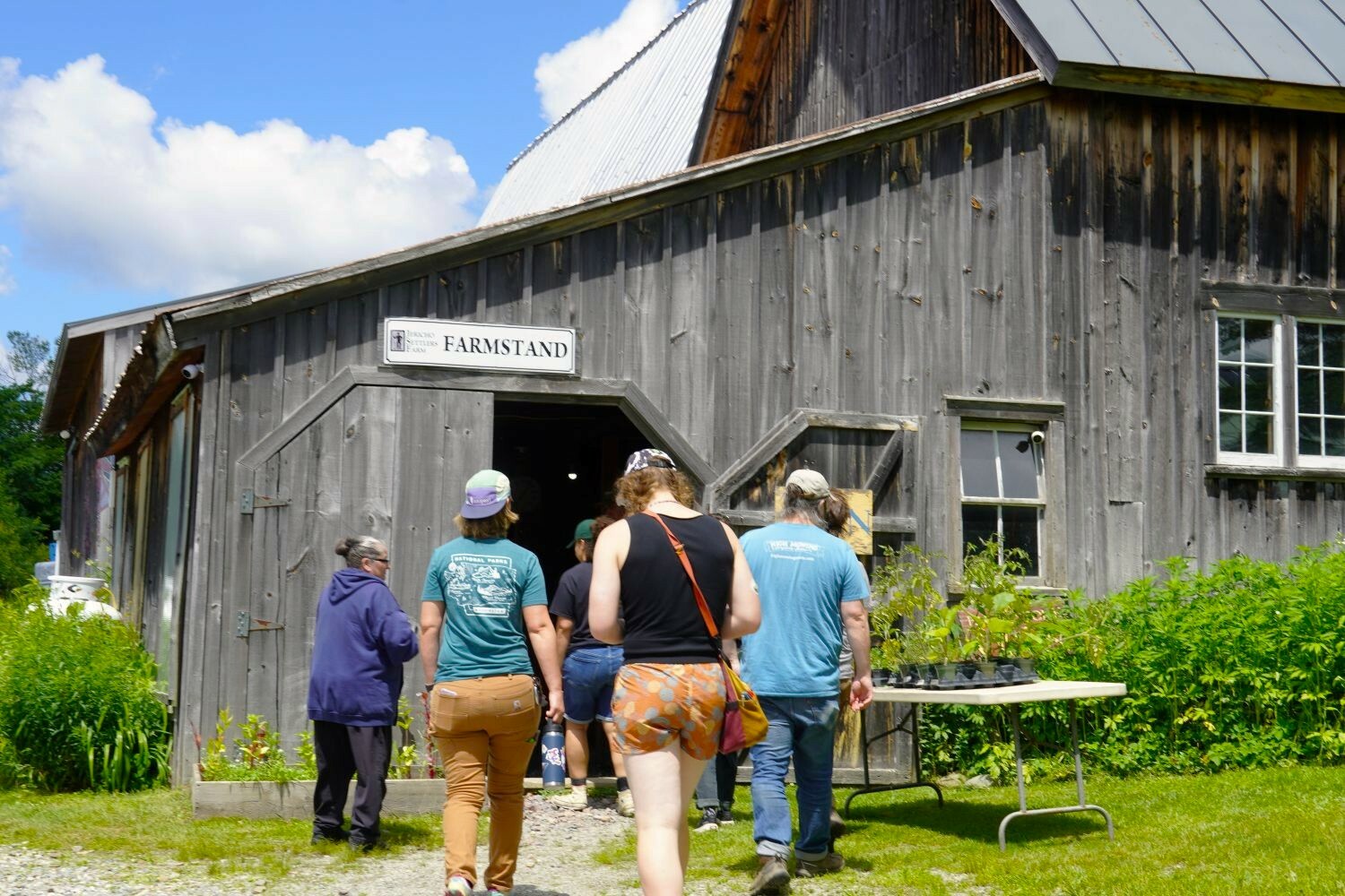 people walking inside a wooden barn farmstand