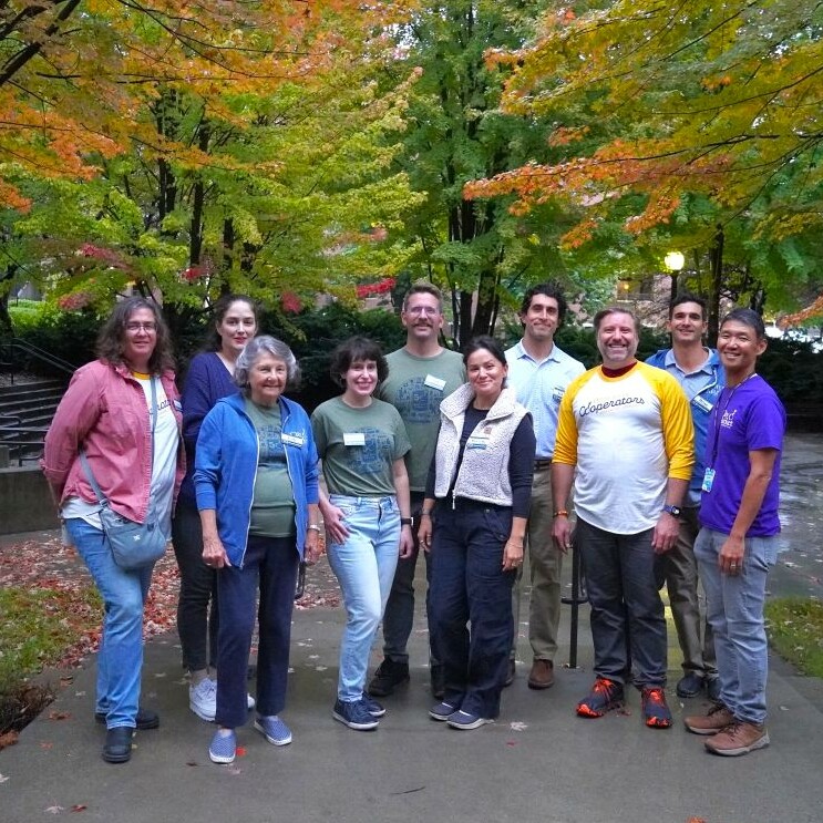 adults stand outside among foliage