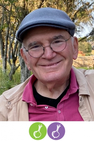 A photo of a person from the chest up. The person is wearing a pink button-down shirt, a brown lightweight jacket, and a blue woolen cap. He is standing in front of a small copse of young trees. Below the photo are a green and purple circle. Each has the silhouette of an onion in it.