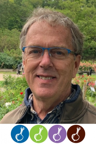 A photo of a person from the shoulders up. The person is wearing a blue collared shirt, a brown jacket, and blue rimmed glasses. He is standing in front of a green field. Below the photo are four colored circles with white onion silhouettes inside. The circles are blue, green, purple and brown, respectively.