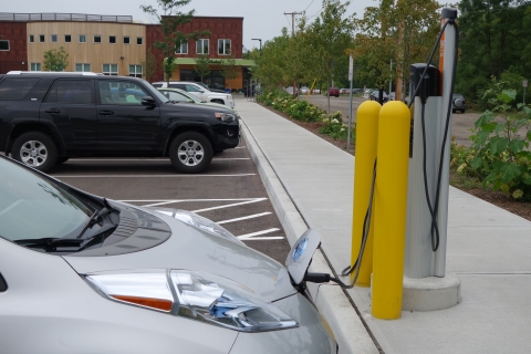 A silver car is plugged into an EV charging station.