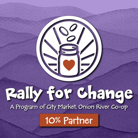 The Rally for Change logo with a white icon depicting a jar with a red heart on the front and three coins falling into it from above. The icon is in front of a mountainous purple watercolor. At the bottom are the words "A program of City Market, Onion River Co-op" and "10% Partner"