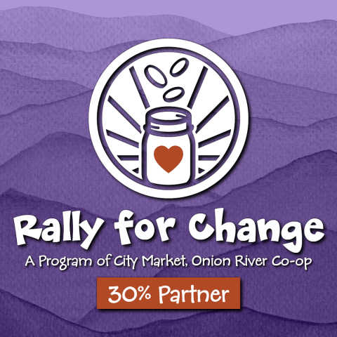 The Rally for Change logo with a white icon depicting a jar with a red heart on the front and three coins falling into it from above. The icon is in front of a mountainous purple watercolor. At the bottom are the words "A program of City Market, Onion River Co-op" and "30% Partner"